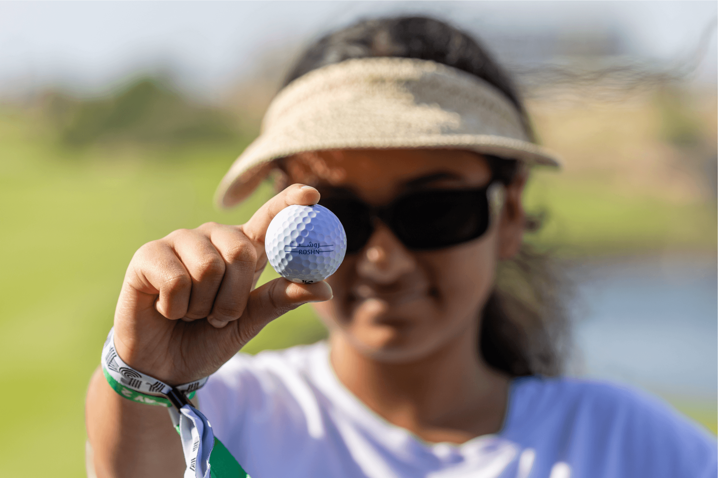 A woman in a visor holding a golf ball